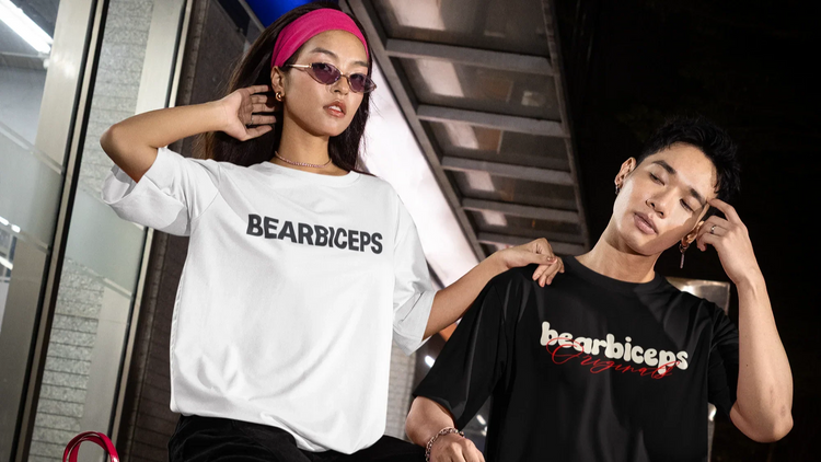 Two people wearing 'Bearbiceps' t-shirts on a city street at night.